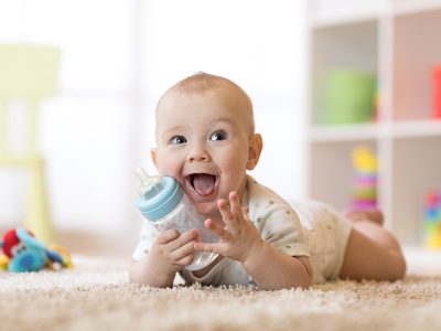 Baby with bottle on carpet